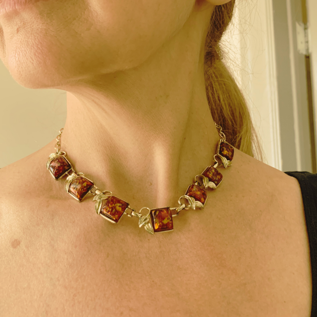 Necklace with amber-colored stones worn by a person.