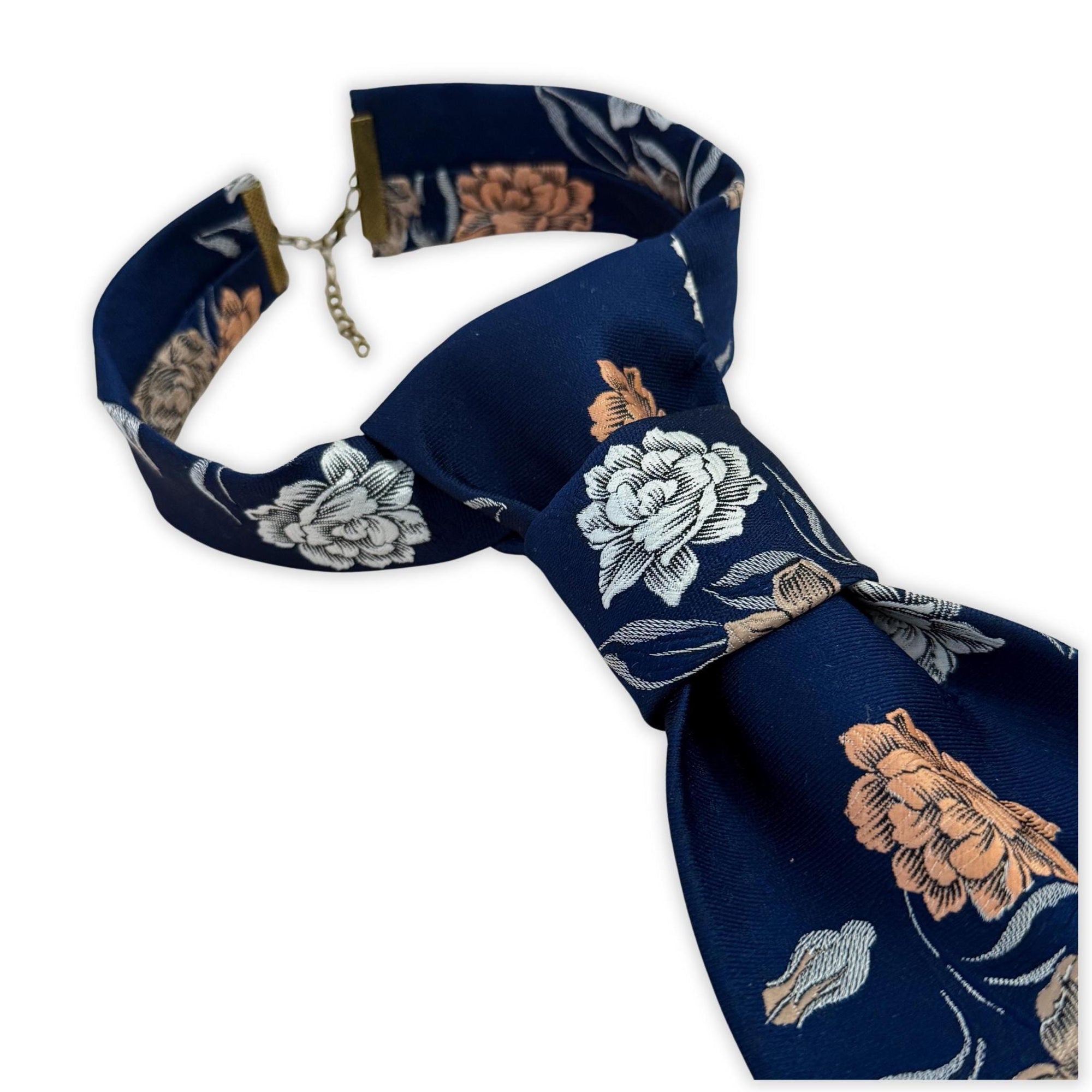 Sustainable vintage accessory: A handmade women’s butterfly-style necktie featuring a 70s peach and cream flower pattern on a navy background.