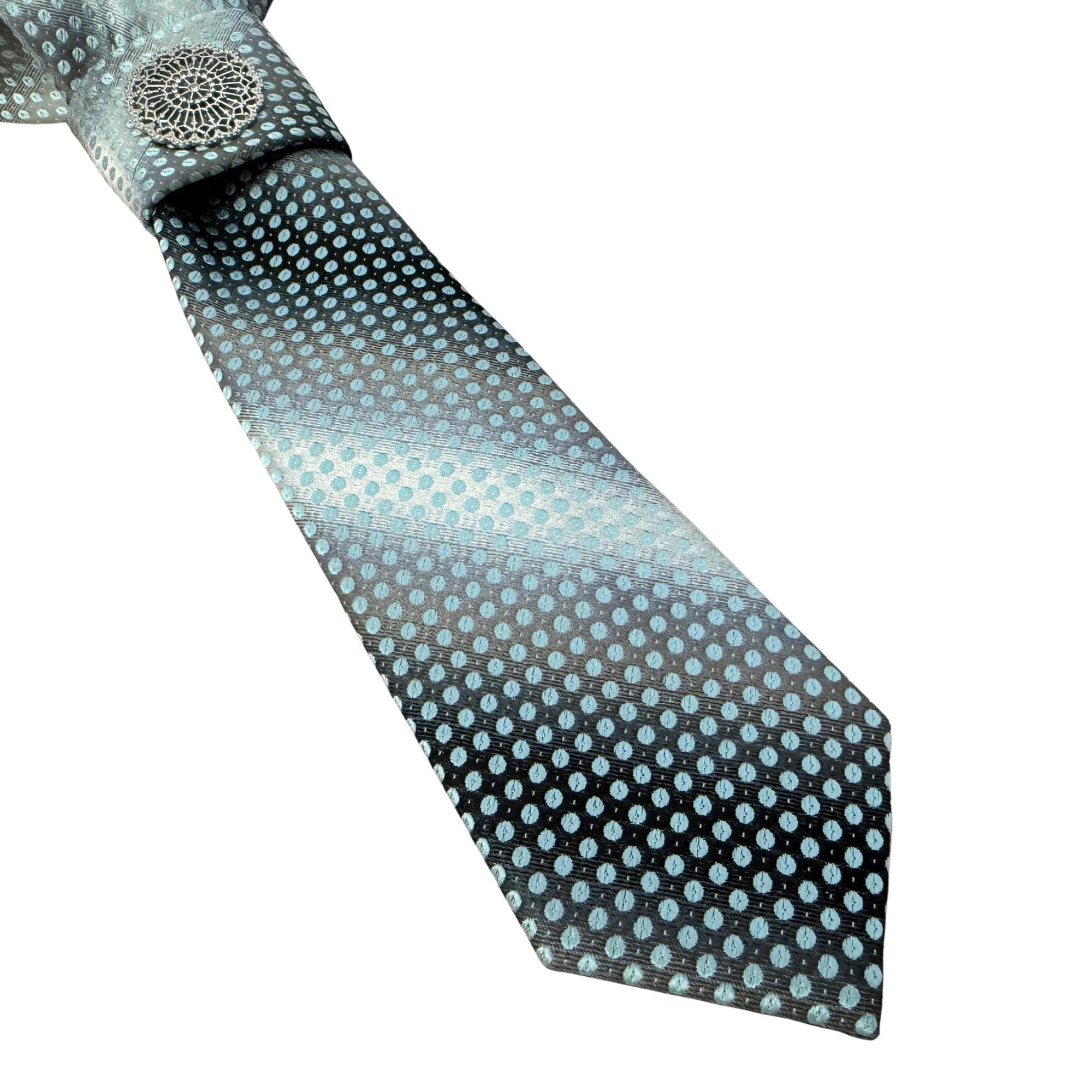 Close-up of a silver metal filigree jewel cantered on a hand-folded grey ombré silk-style tie.