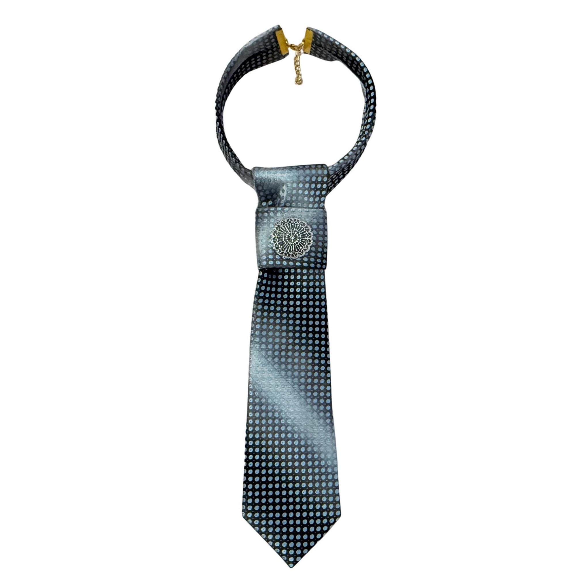 A hand-styled women's necktie displayed on a cream bust, showcasing the transition from dark charcoal edges to a light silver centre.