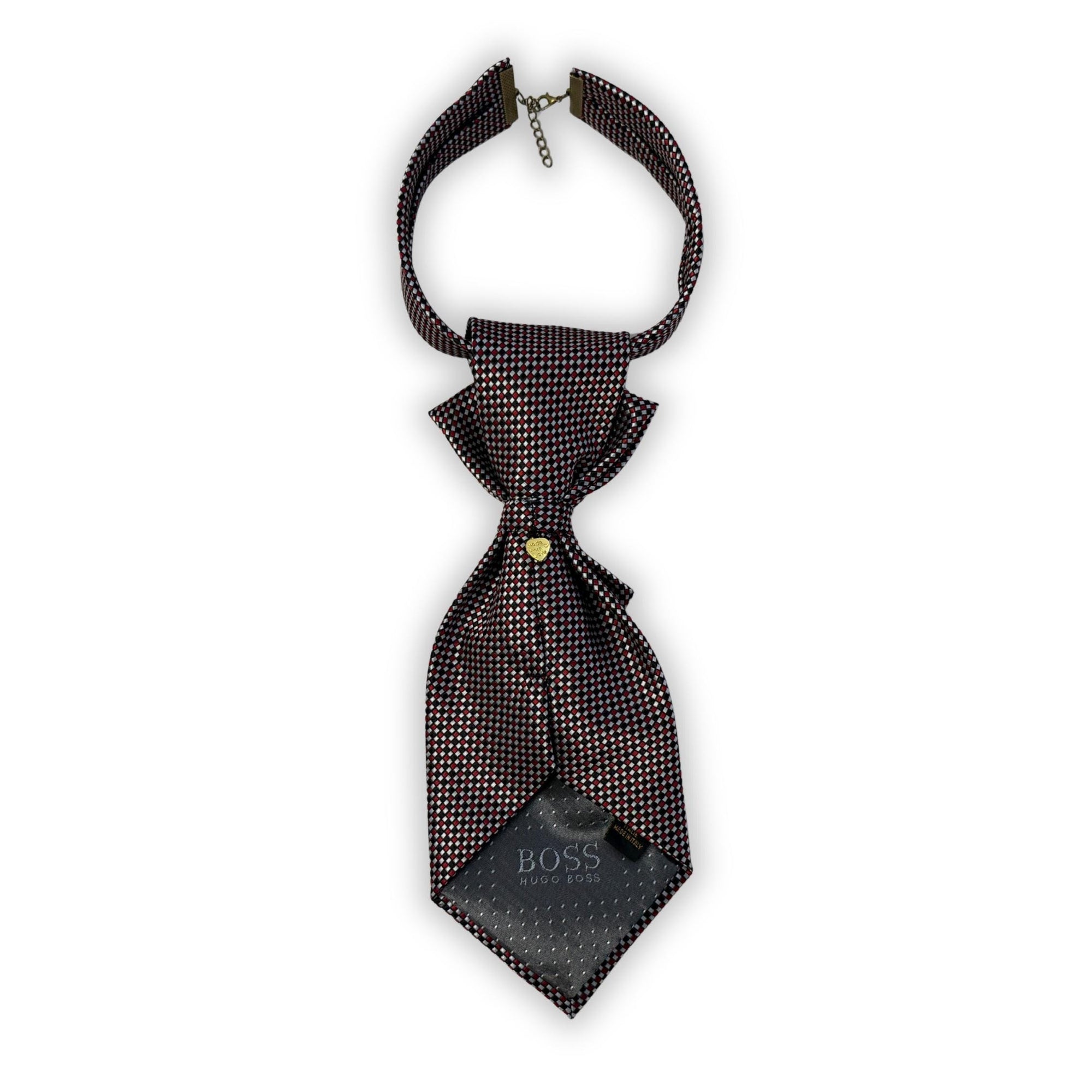 A hand-styled women's necktie in onyx and silver, displayed on a textured white background to highlight the tiered fold and bronze-tone clasp.