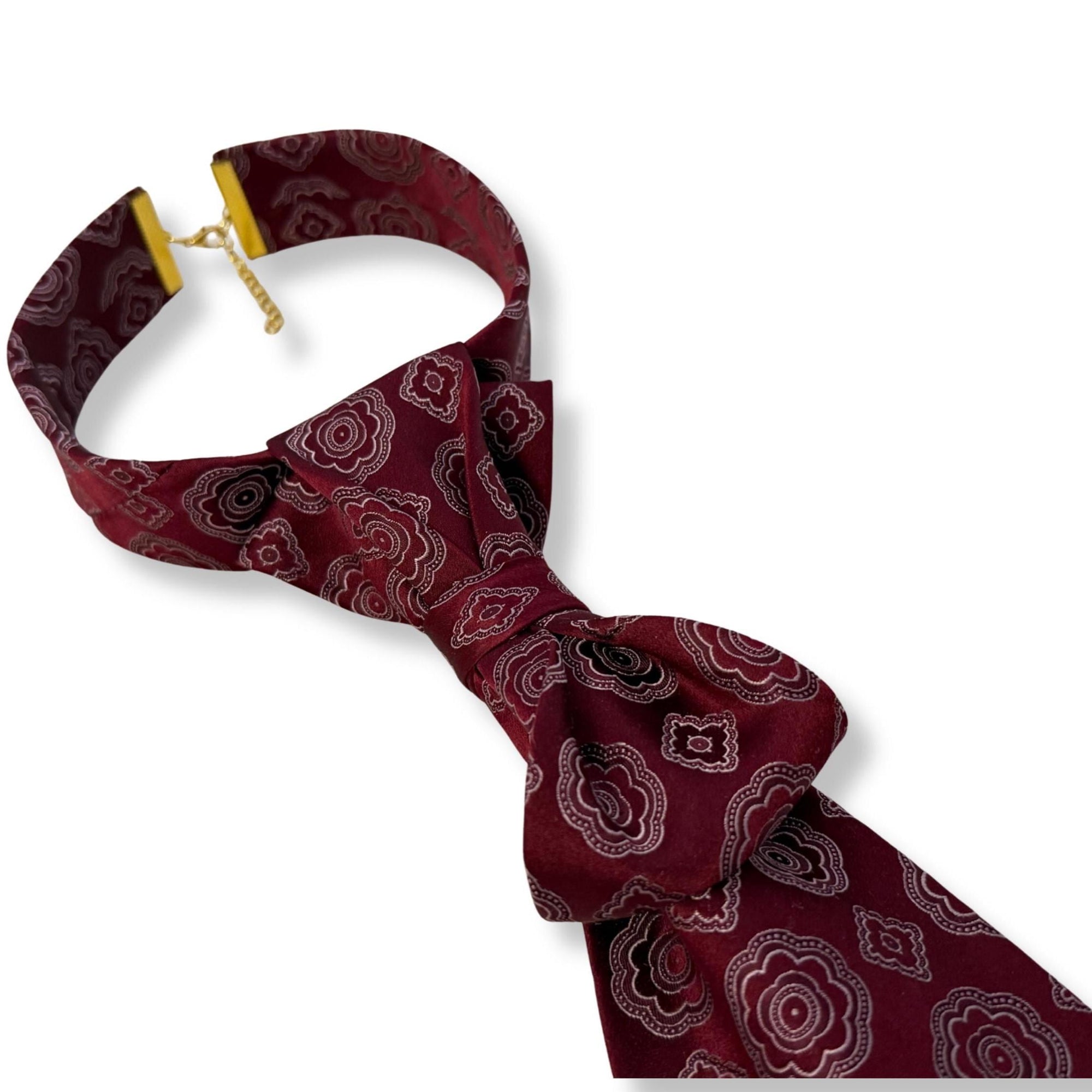 A close-up, high-resolution shot of the 100% silk weave on a reworked DKNY tie, showcasing the "Made in USA" heritage and the intricate silver floral medallion detail.