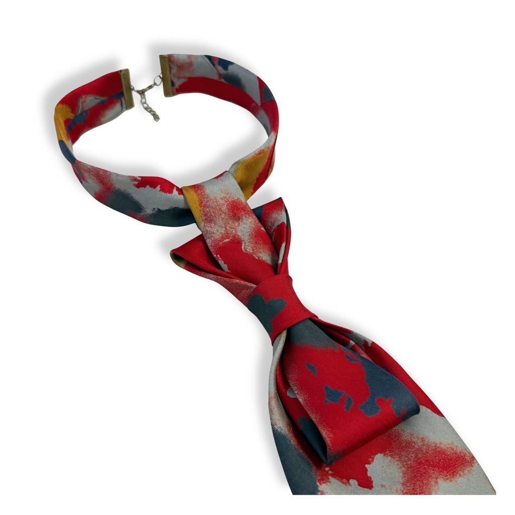 Detailed shot of the adjustable metal clasp on a red abstract silk tie, showcasing the high-sheen texture and bespoke Canadian craftsmanship.