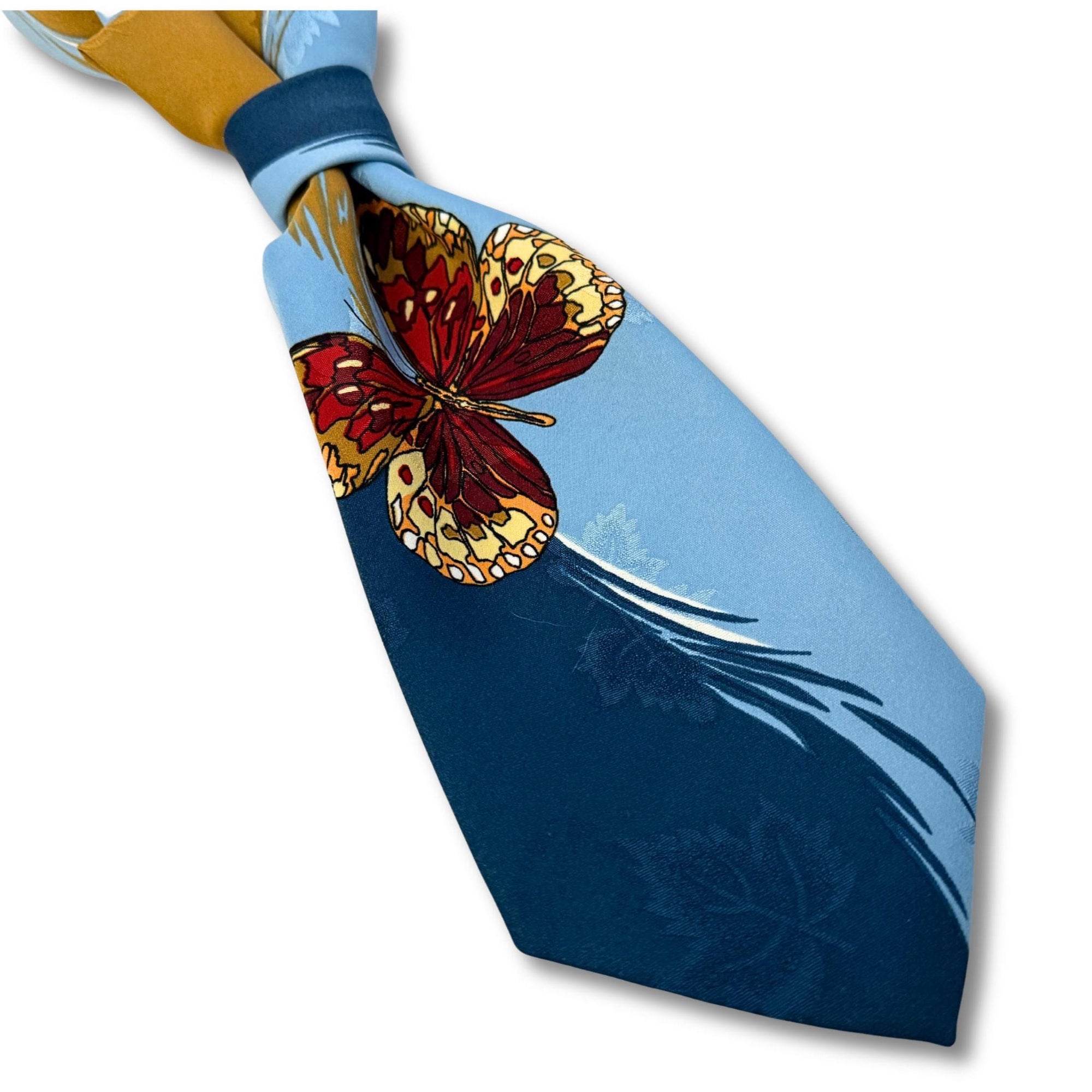 Close-up of the intricate butterfly wing detail on a blue Rene de Deauville tie, showcasing the vibrant French design.