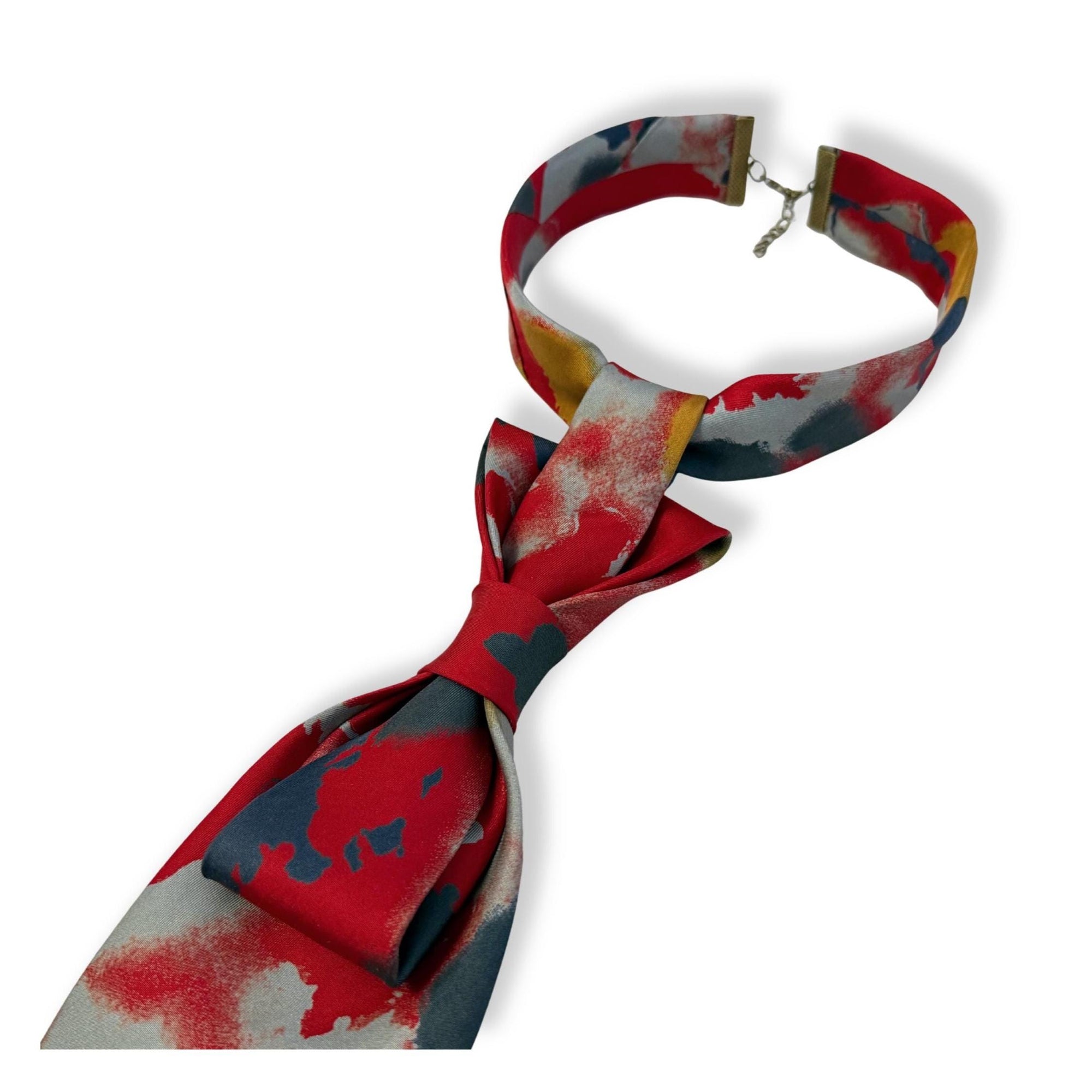 Flat lay of a handmade women’s butterfly-style necktie made from a Canadian silk tie featuring a bold red and grey splatter pattern.