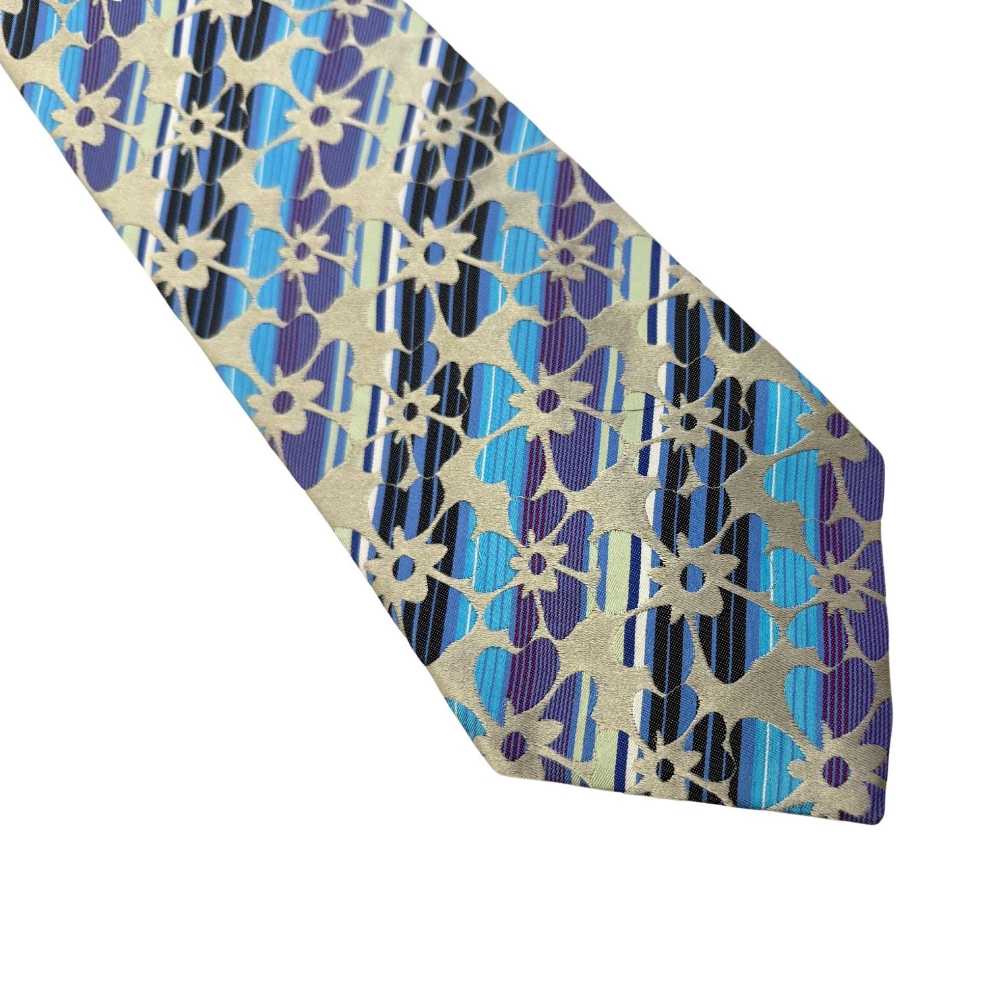 Close-up of an Etro Milano silk tie with blue stripes and violet floral patterns on a champagne gold background.