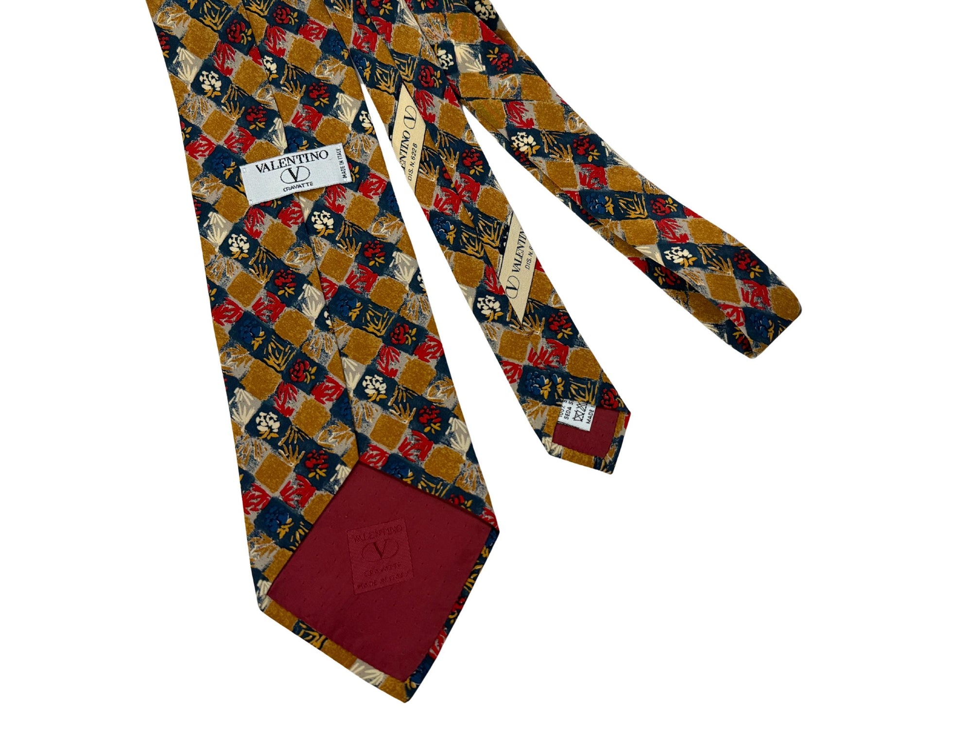 Authentic vintage Valentino Garavani silk tie. Features a 10cm blade in a rare ochre and crimson geo-floral print. Hand-finished in Italy for the modern, self-assured professional.