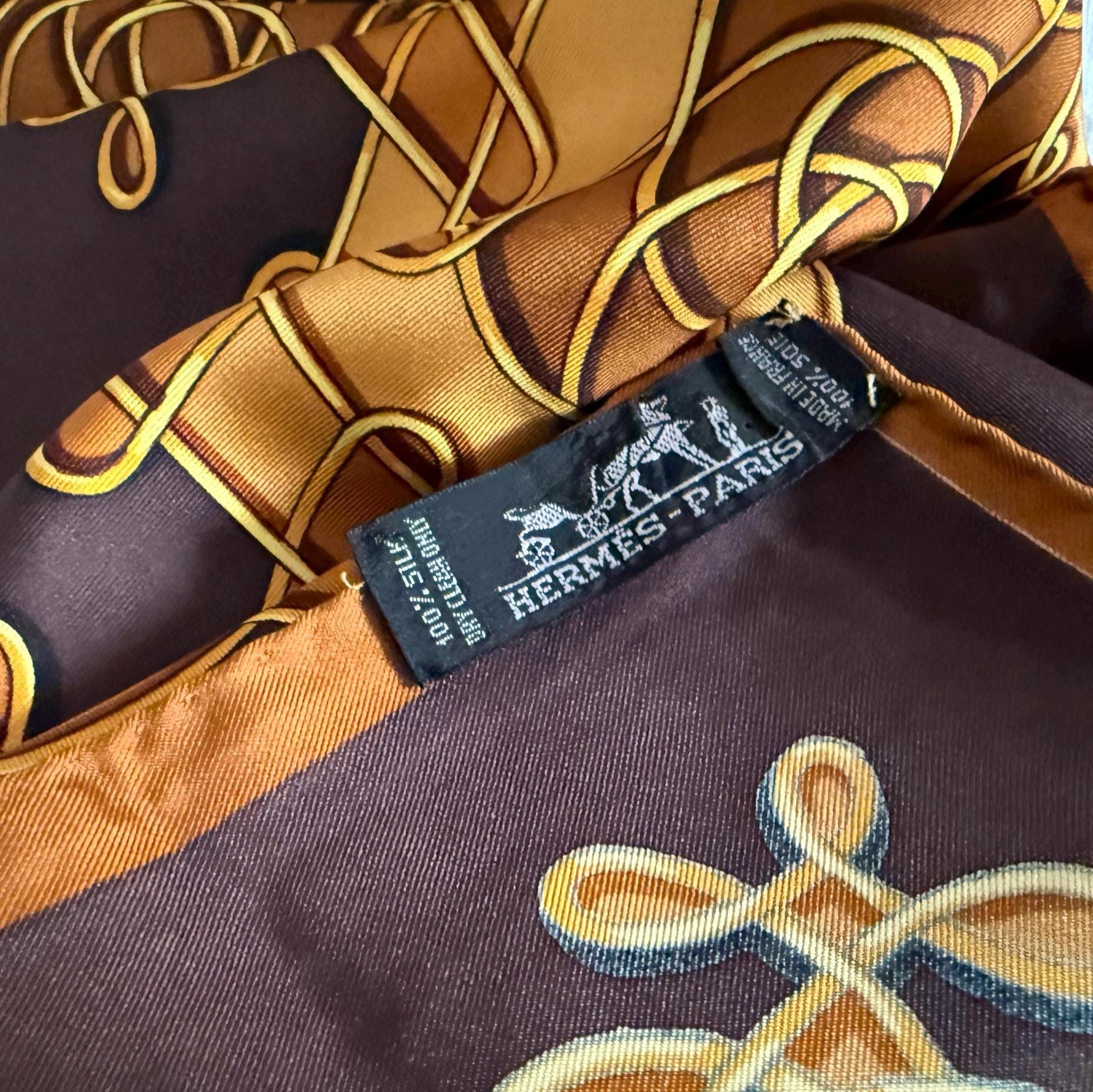 Shop this archival Hermès "Vinci" scarf. Designed by Françoise Héron, this 100% silk twill piece features golden Renaissance knots on a chocolate brown field. Hand-rolled edges.